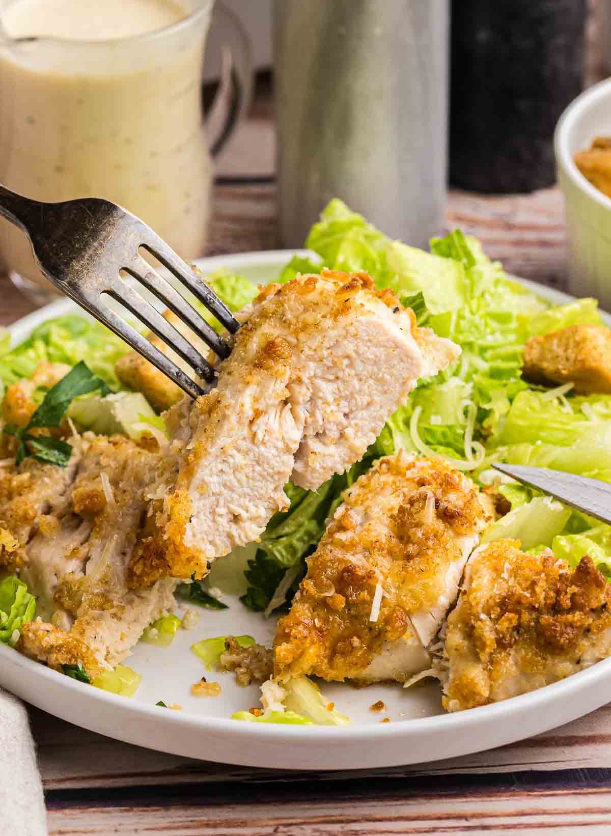 A plate of baked caesar chicken served with salad.