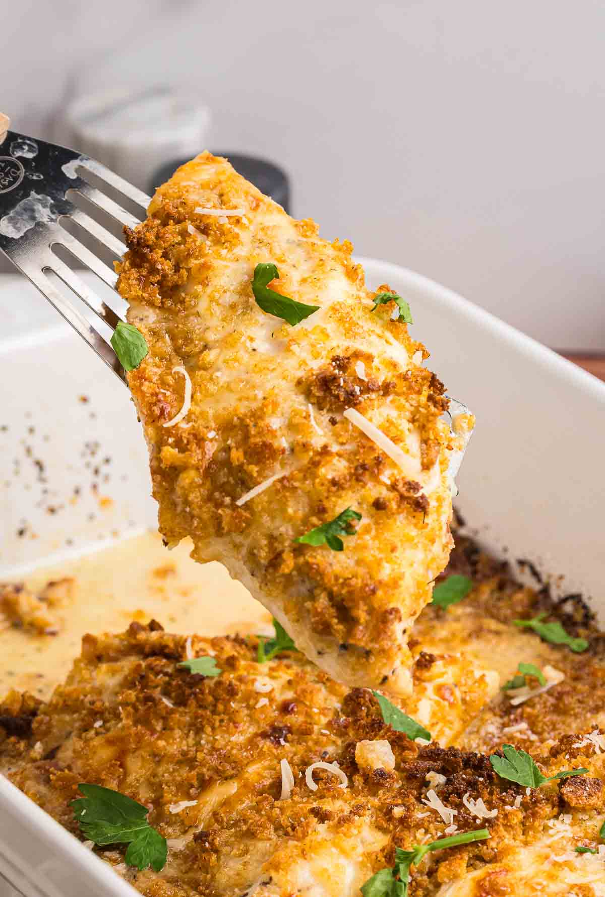 Picking up a piece of baked caesar chicken with a fork.