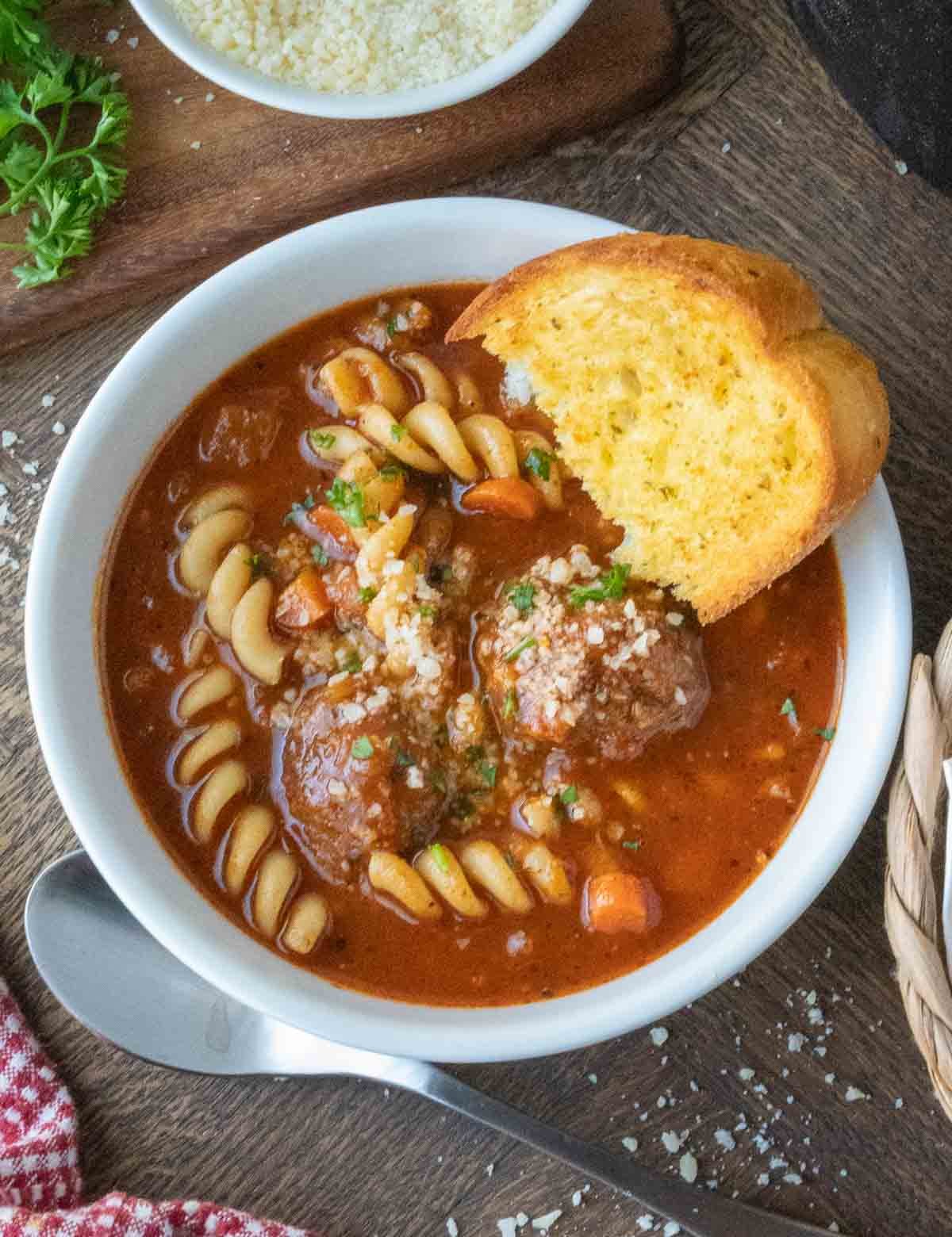 Meatball soup in a bowl with garlic bread.