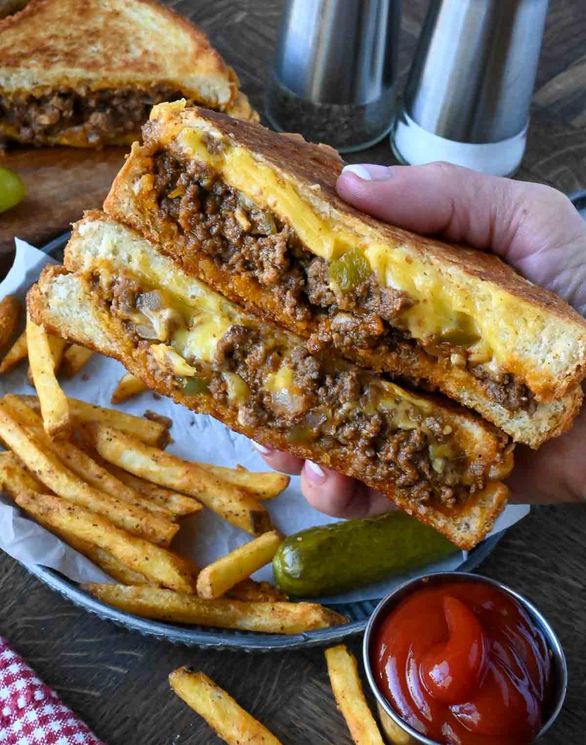 Sloppy joe cut in half and being held.