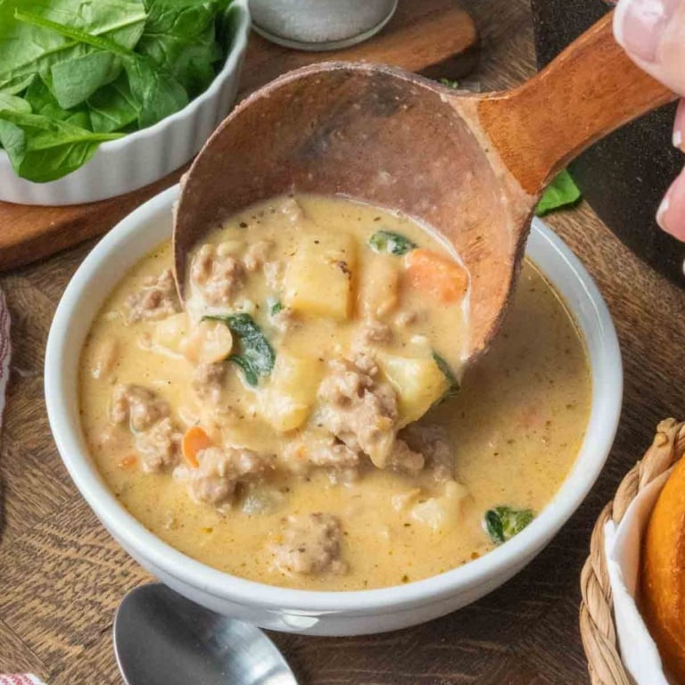 Spooning white bean soup into a bowl with a wooden ladle.