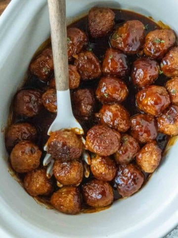 Cooked fire cracker chicken meatballs with a serving spoon.