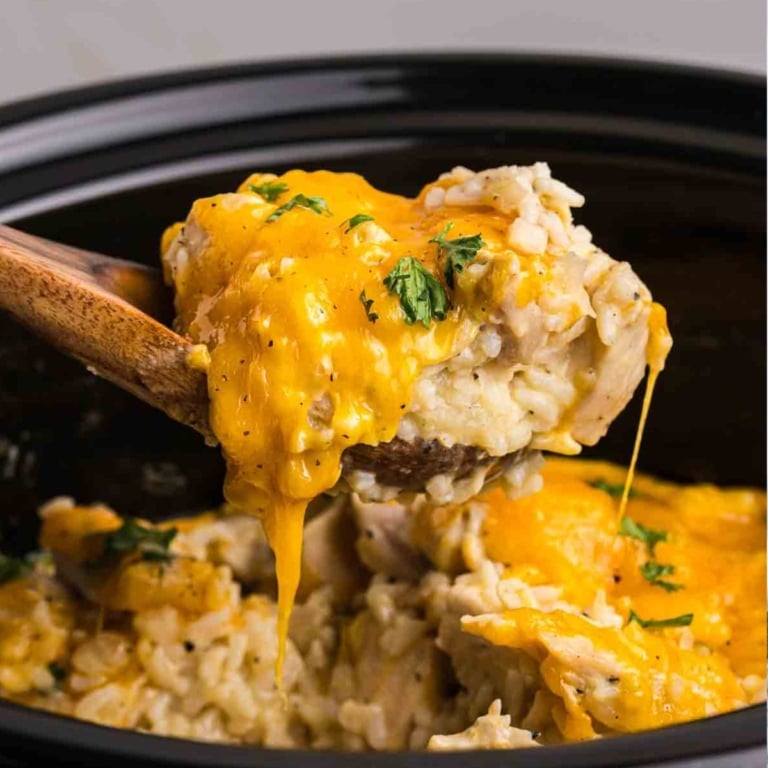 Taking a large scoop of slow cooker chicken and rice with a wooden spoon.