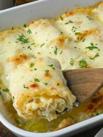 A spatula scooping up a lasagna roll up.