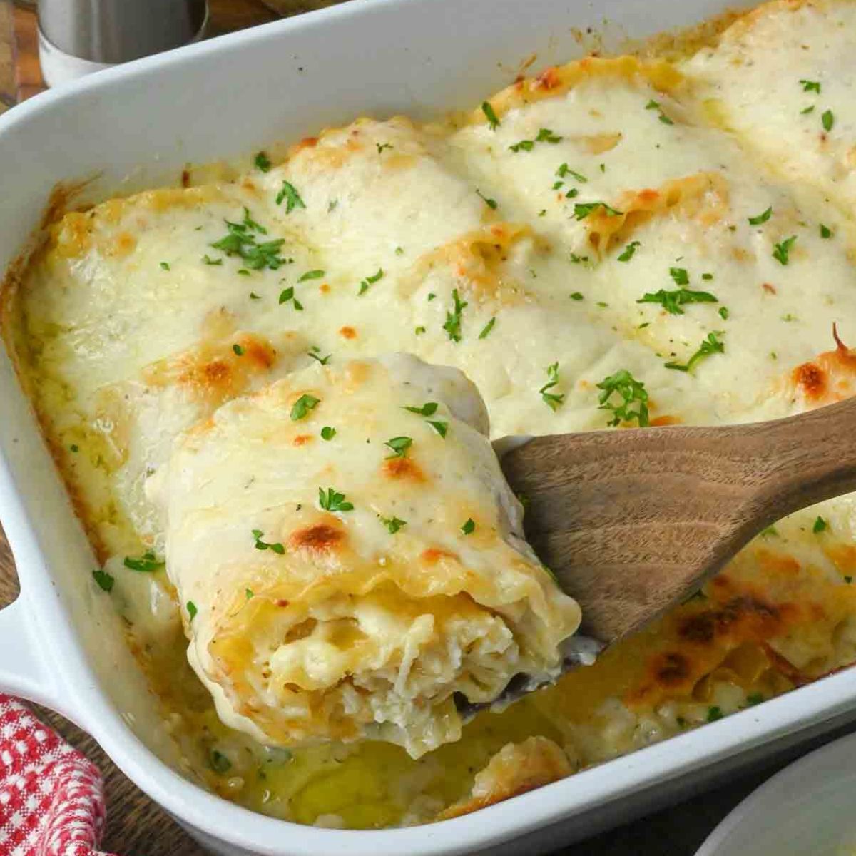 A spatula scooping up a lasagna roll up.