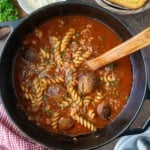 Italian meatball soup with a wooden spoon in a pot.