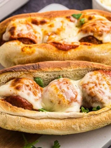 Two slow cooker meatball subs on a serving platter.