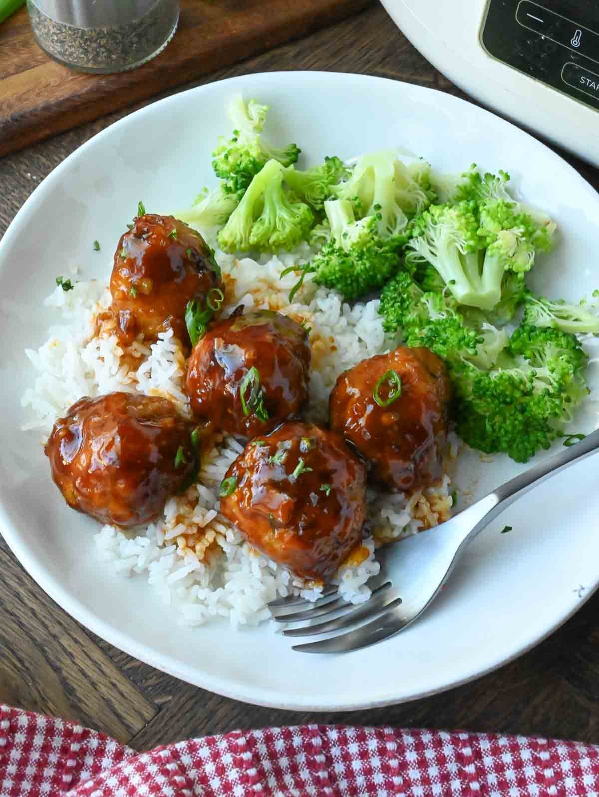 Fire cracker chicken meatballs on white rice with broccoli.