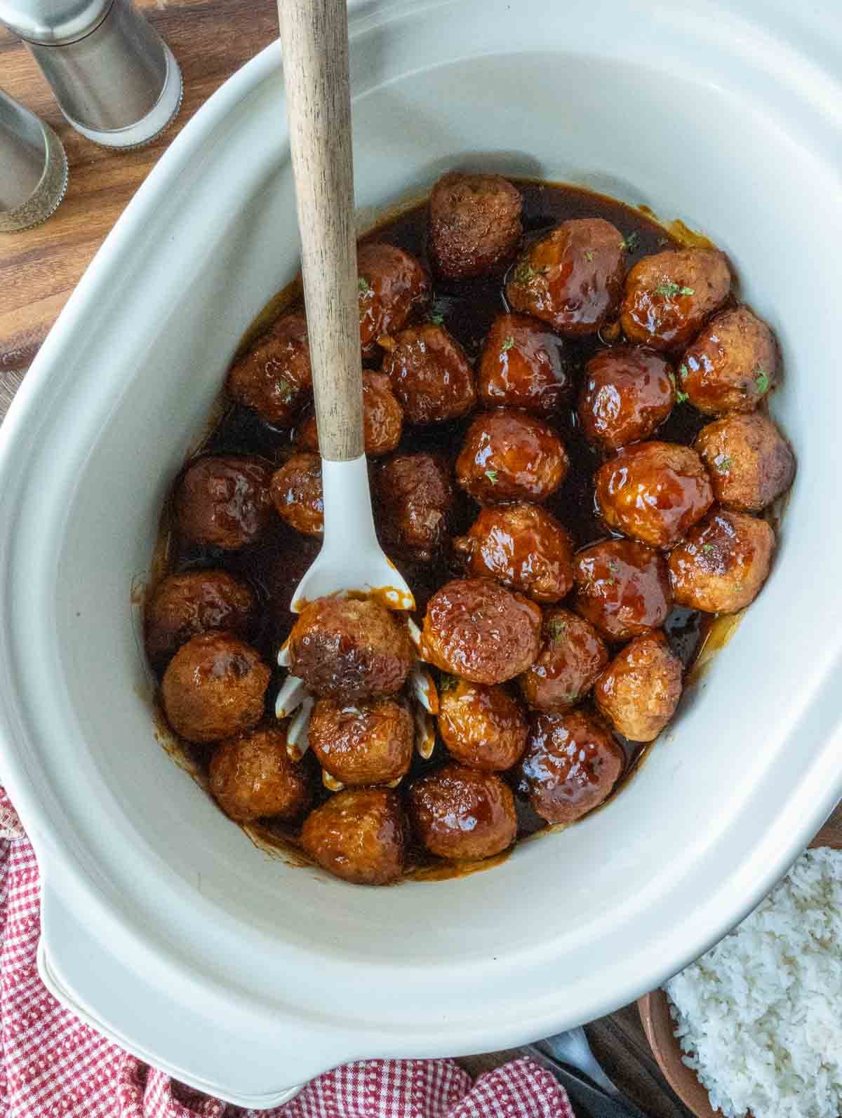 Cooked fire cracker chicken meatballs with a serving spoon.