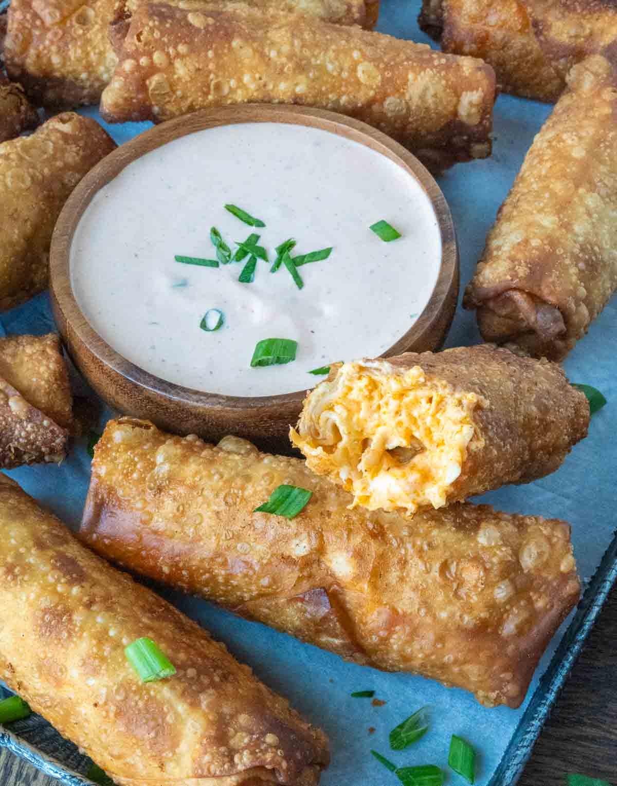 Buffalo chicken egg rolls served with a side of dipping sauce.