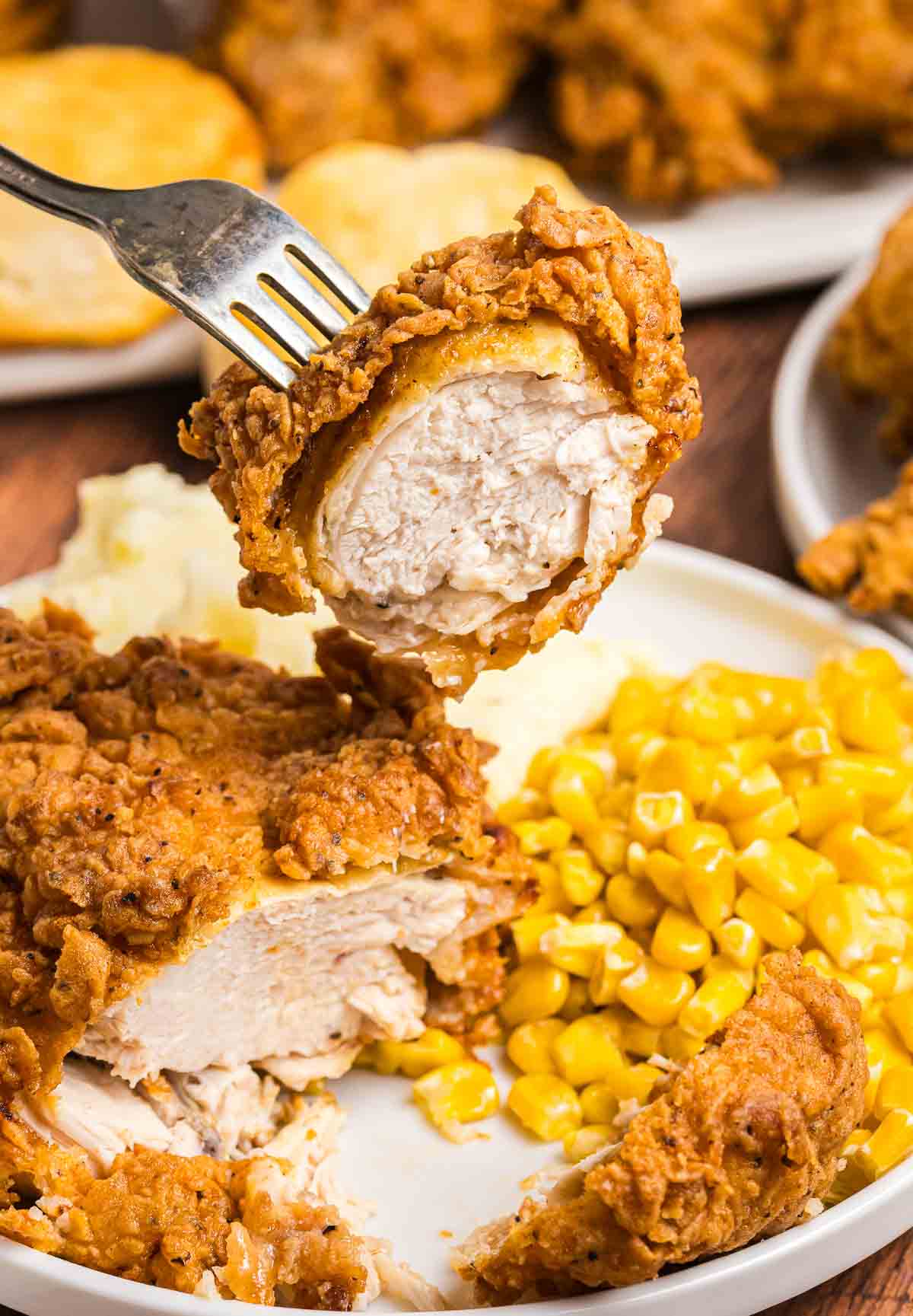 Taking a piece of cracker barrel fried chicken with a fork.