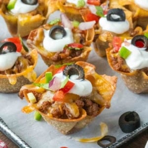 Close up of taco wonton cups on a parchment lined baking sheet.