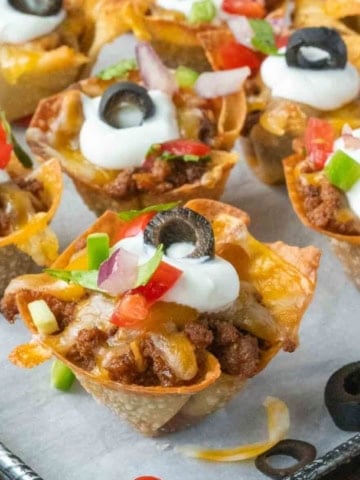 Close up of taco wonton cups on a parchment lined baking sheet.