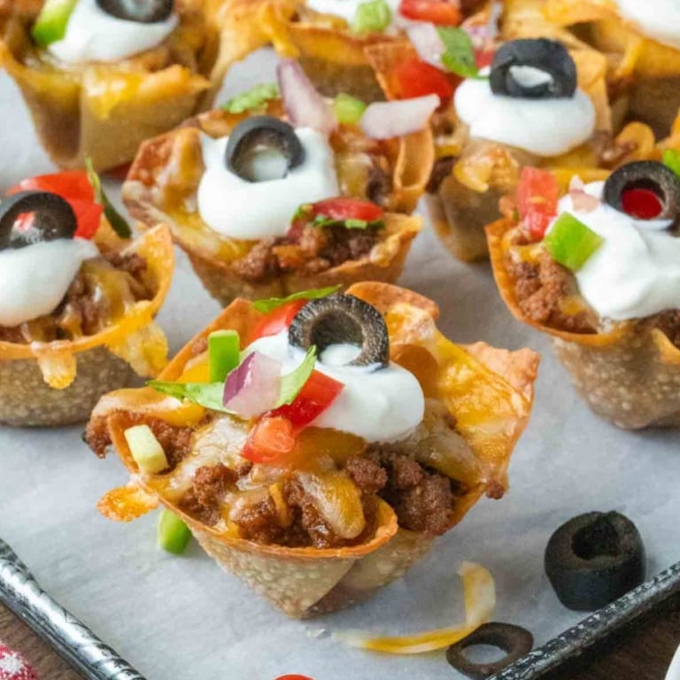 Close up of taco wonton cups on a parchment lined baking sheet.