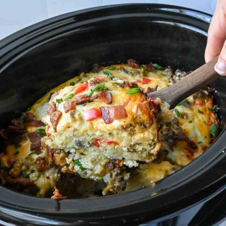 Taking a scoop of slow cooker breakfast casserole.