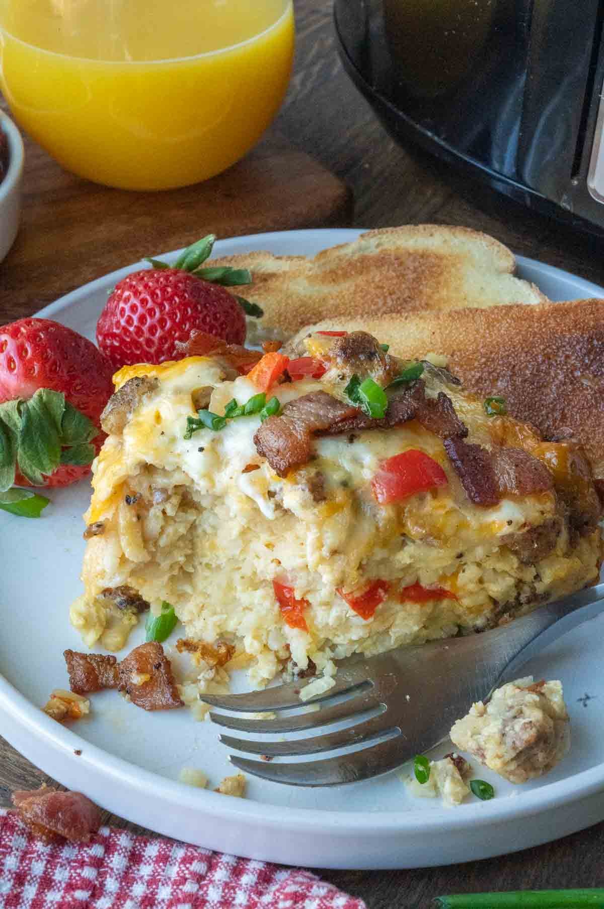 A plate of slow cooker breakfast casserole served with fruit and toast.