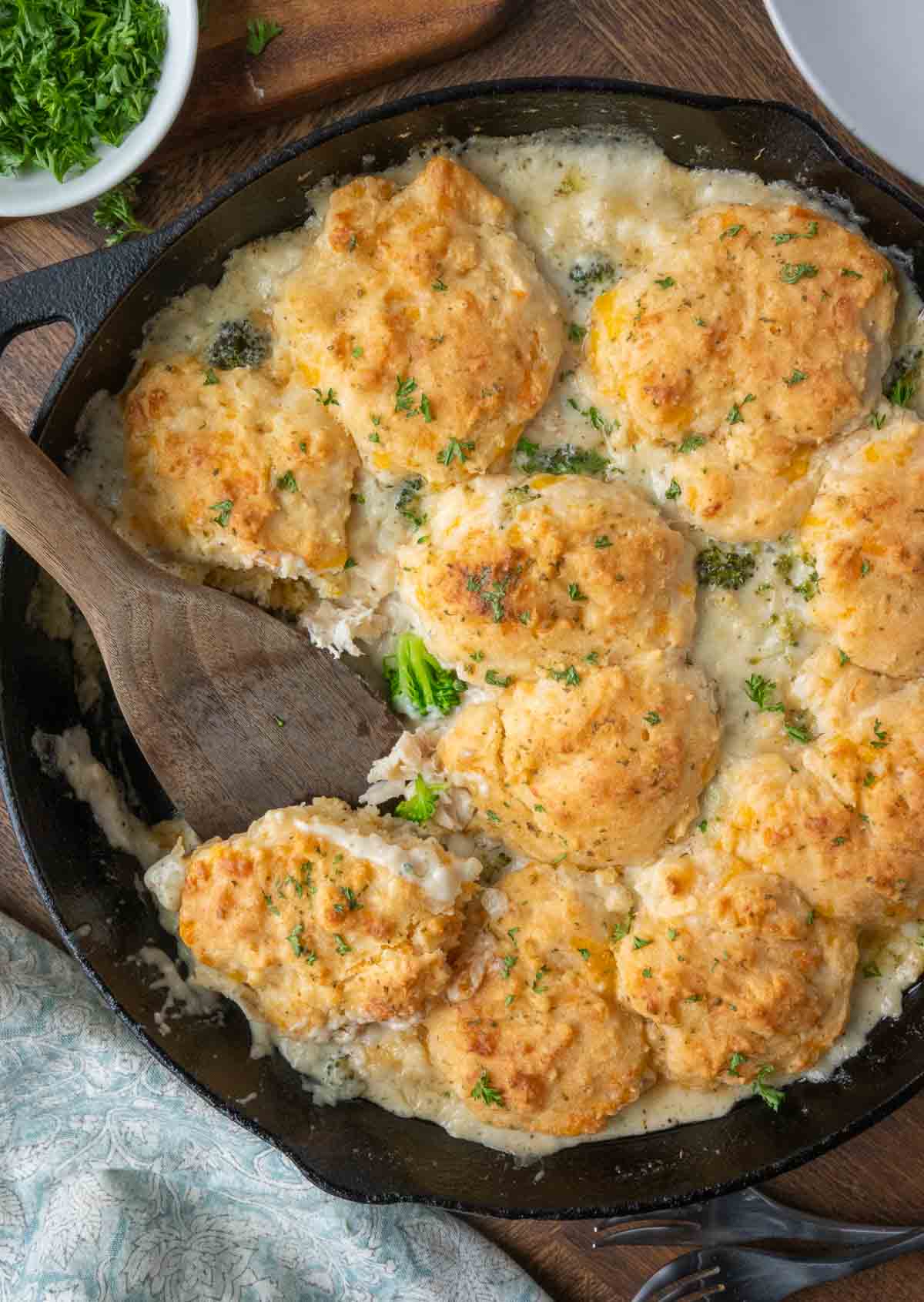 chicken biscuit casserole in a skillet with a wooden spatula.