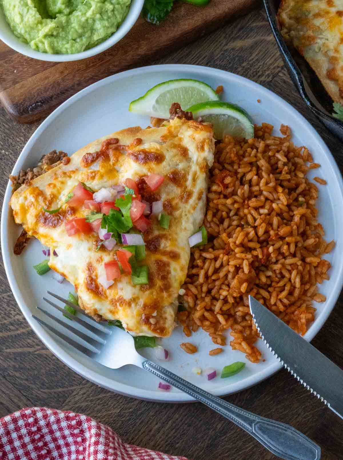 A plate with a cheesy beef pocket served with rice.