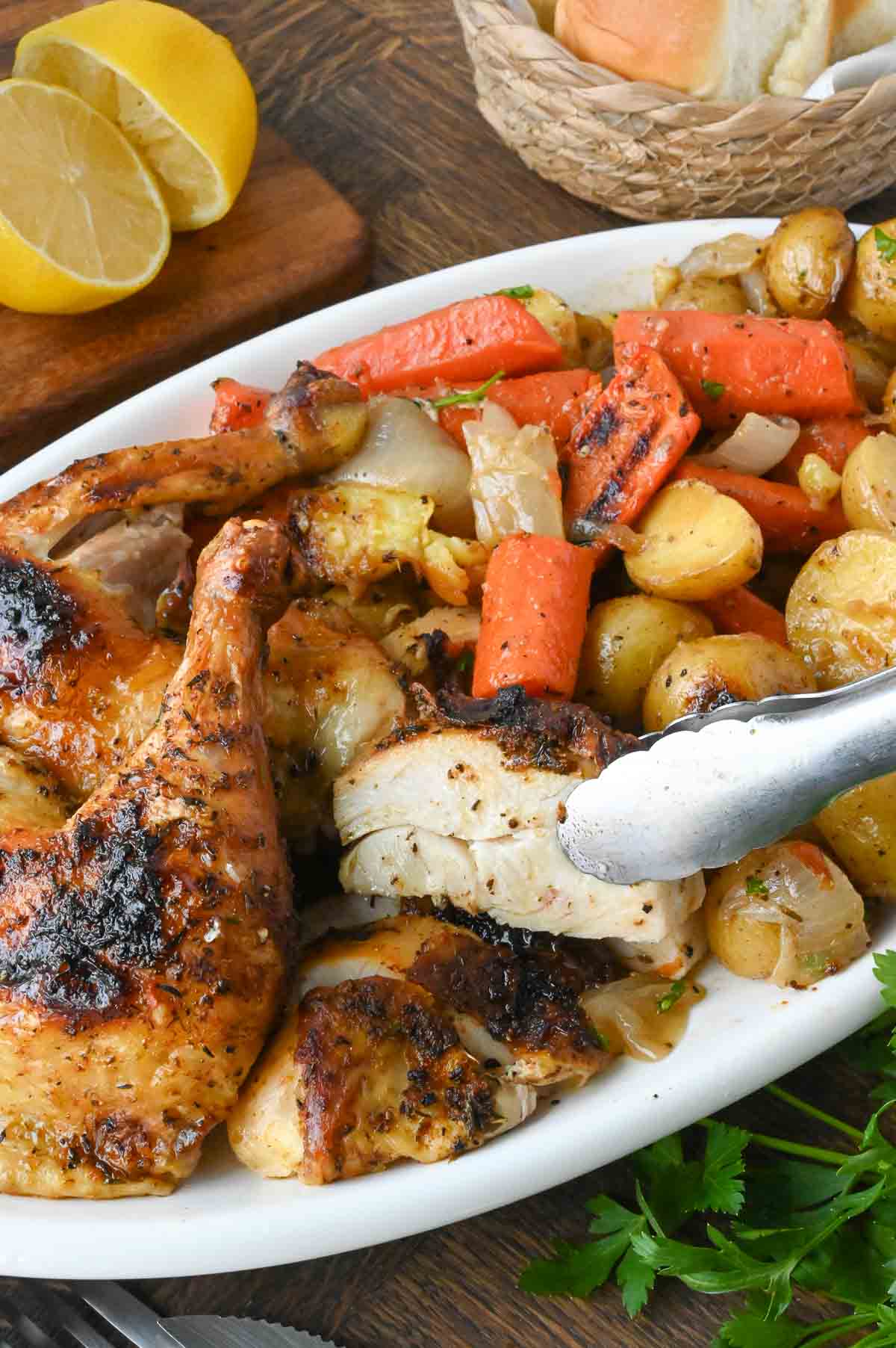 A serving platter with dutch oven roasted whole chicken and vegetables.