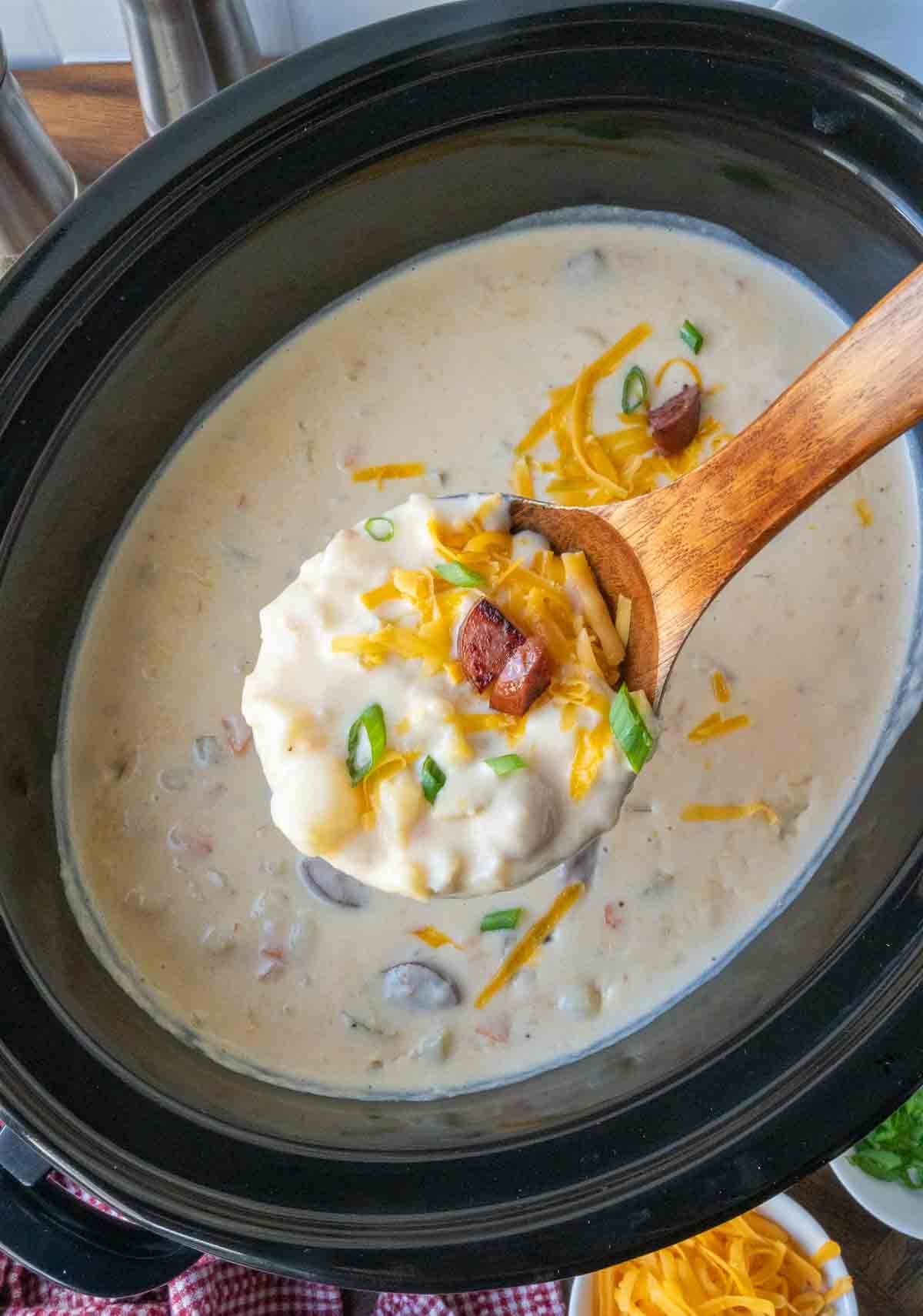 Stirring a slow cooker with kielbasa and potato soup.