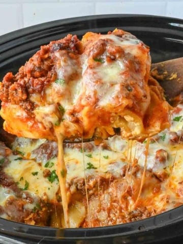 Taking a big scoop of crockpot lasagna from the slow cooker.