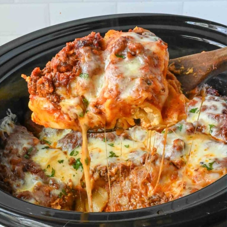 Taking a big scoop of crockpot lasagna from the slow cooker.