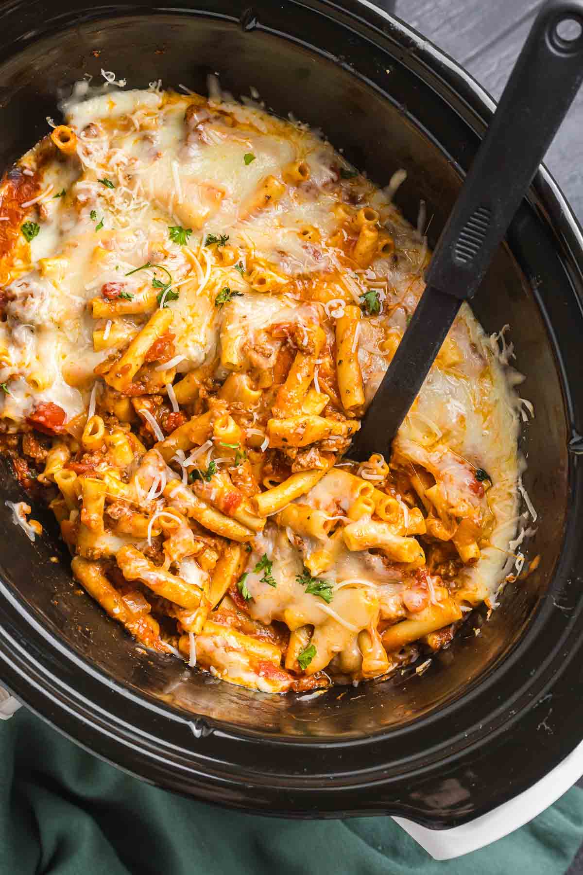 Stirring baked ziti in a slow cooker.