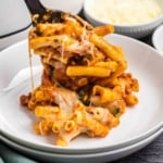 Spooning slow cooker baked ziti onto a white plate.