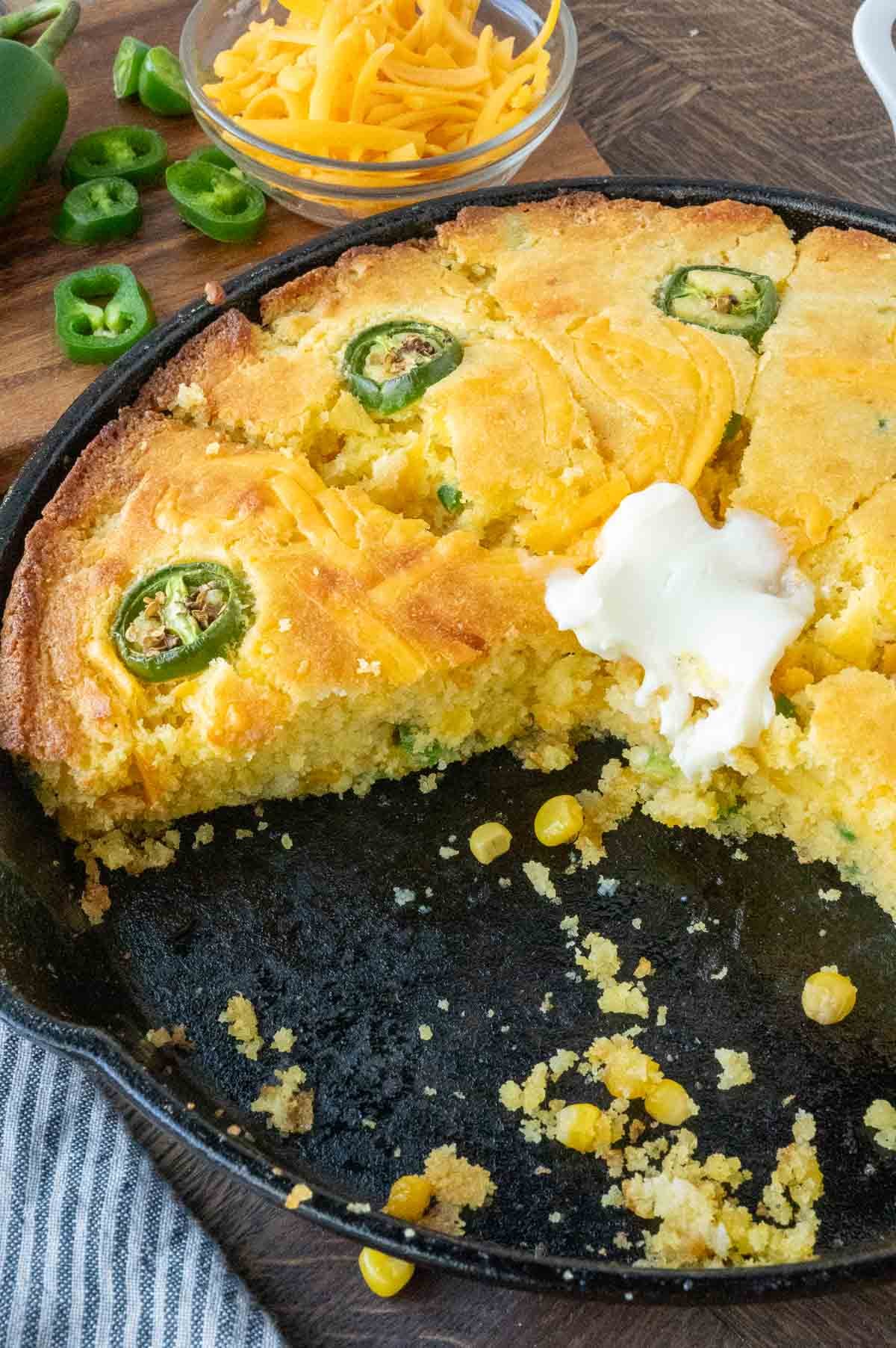 Several slices of cheddar cheese jalapeno cornbread in a skillet.