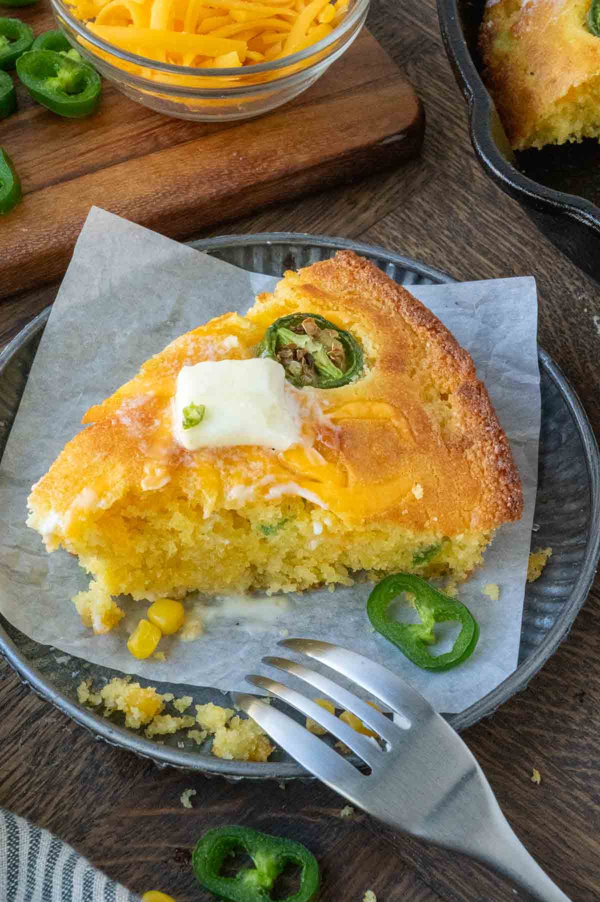 A plate with a slice of cheddar cheese jalapeno cornbread.