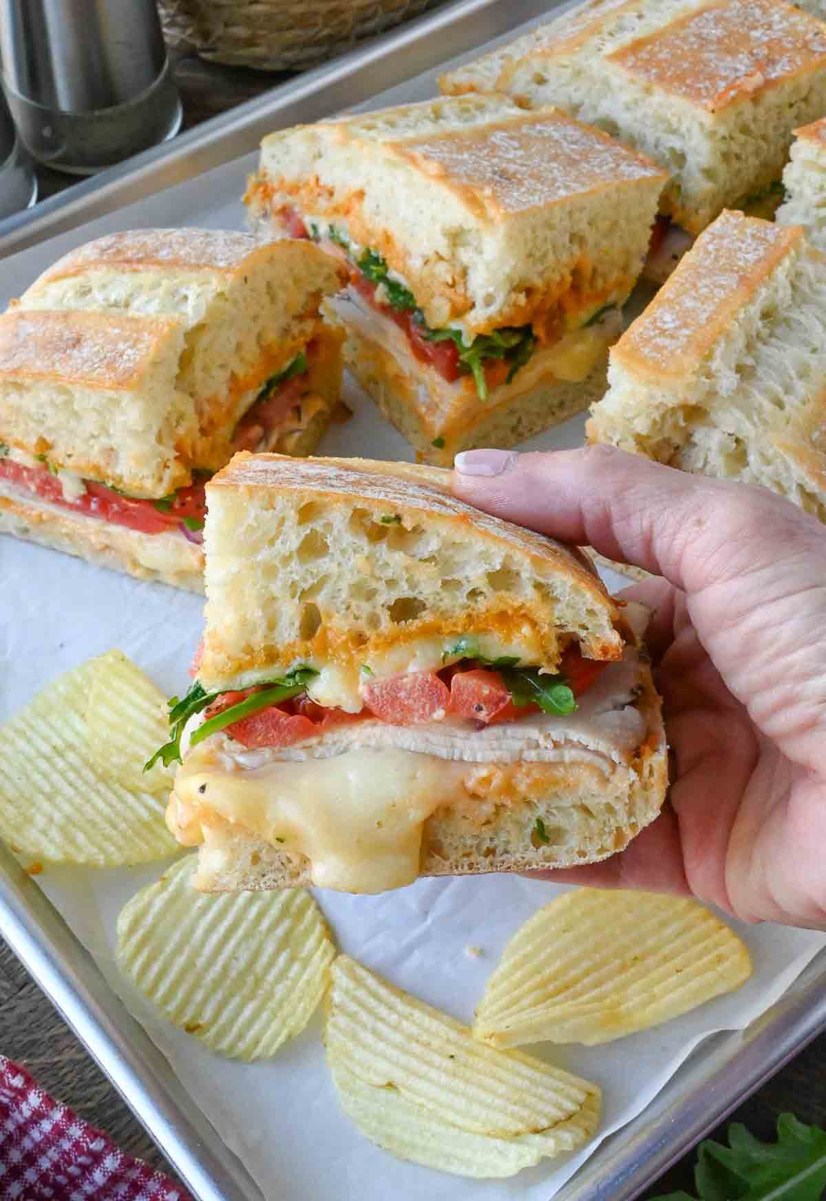 Picking up one half of a ciabatta chicken sandwich.