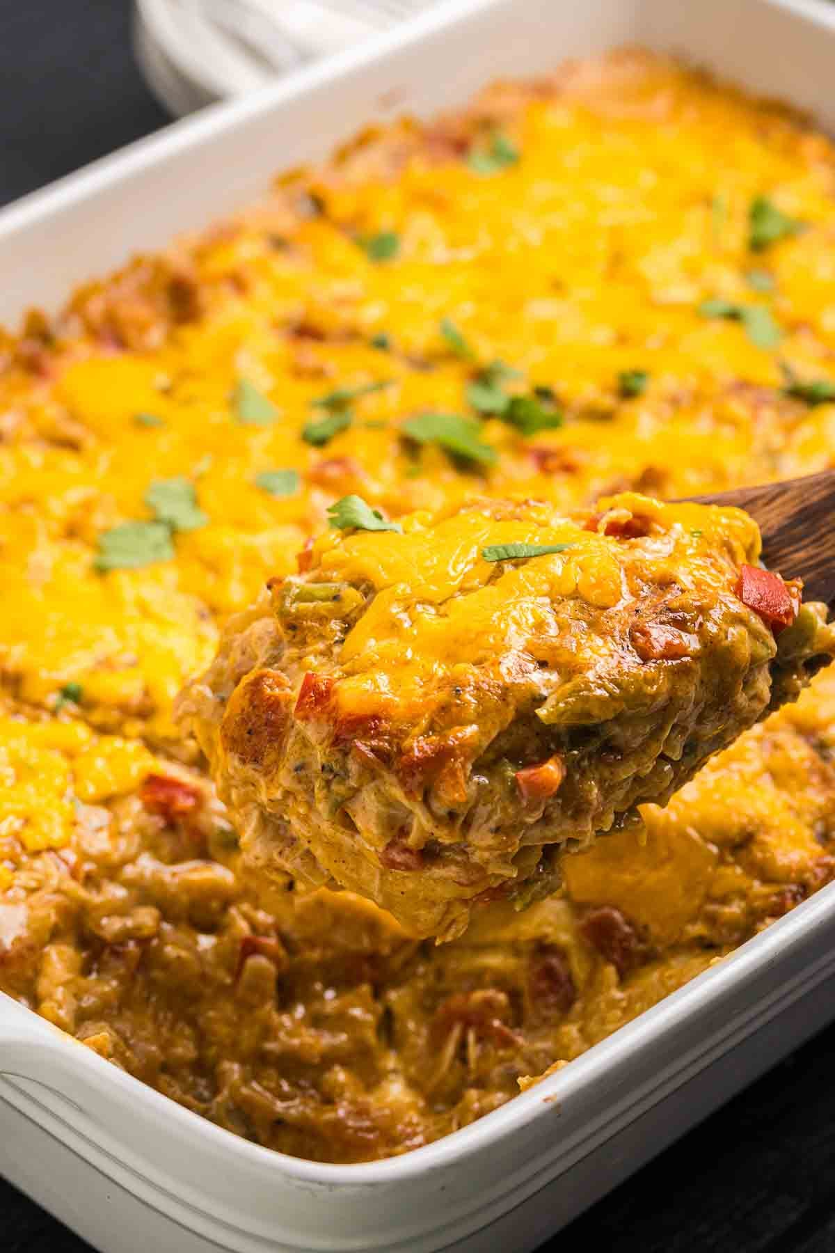Taking a scoop of king ranch chicken casserole from a casserole dish.