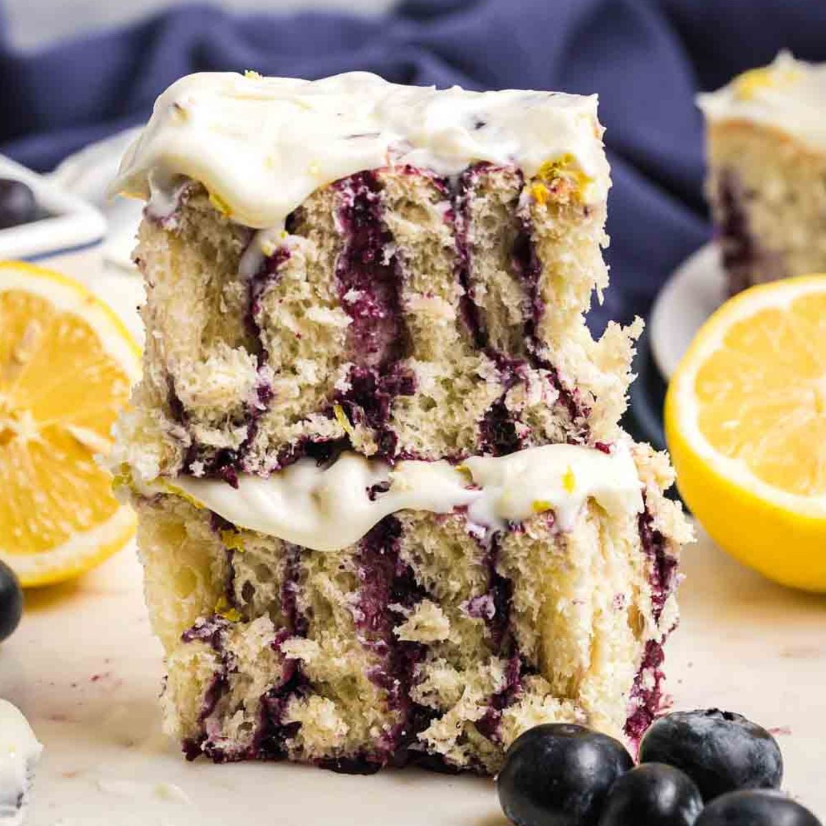 A stack of two lemon blueberry rolls with cream cheese frosting.