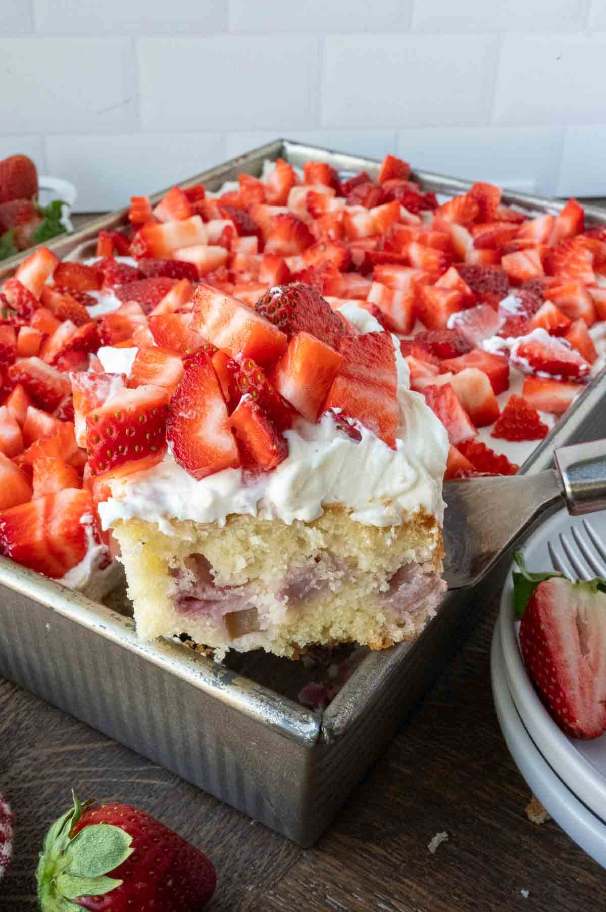 Lifting up a slice of strawberry whipped cream cake.