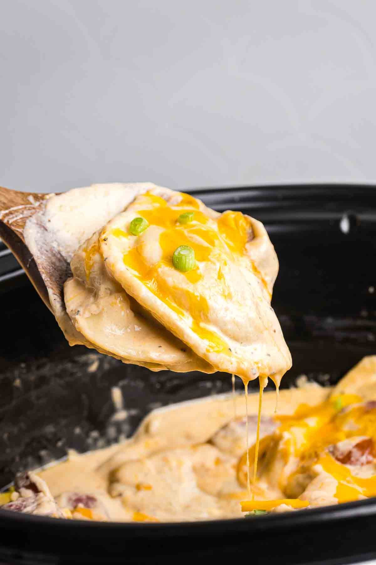 Scooping pierogi casserole out of the crockpot.