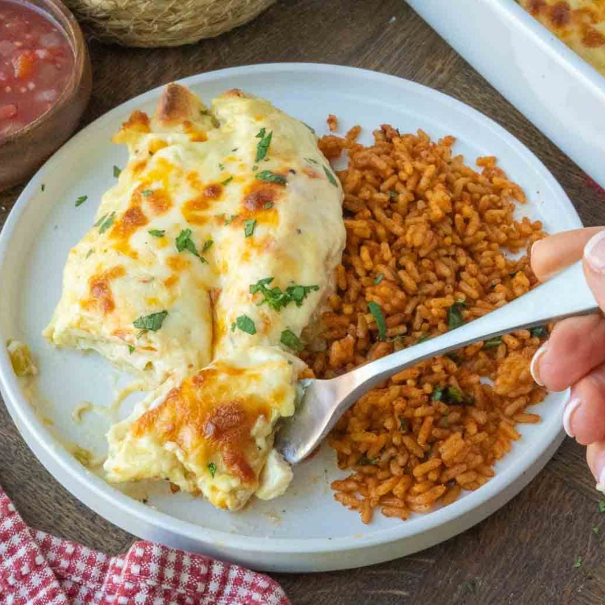 A plate of rotisserie chicken enchiladas with seasoned rice.