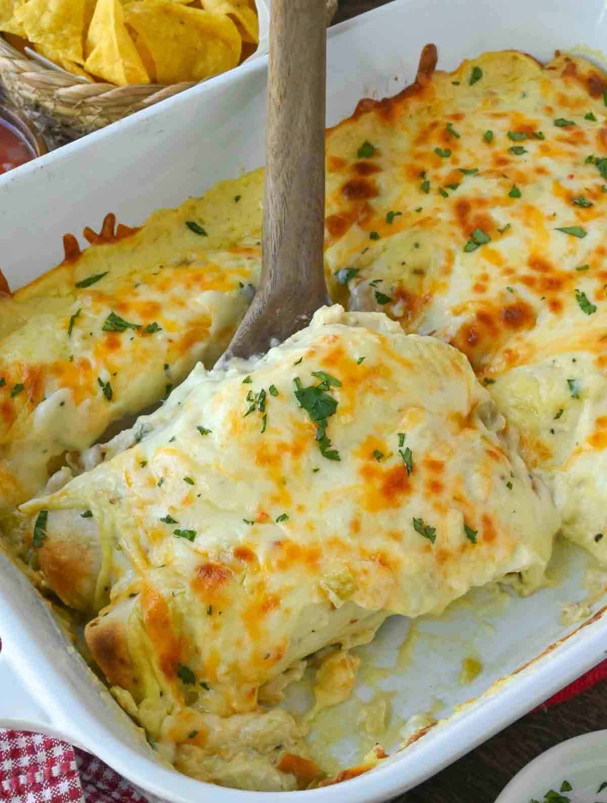 Using a spoon to take a scoop of rotisserie chicken enchiladas.