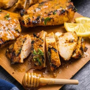 Grilled honey mustard chicken cut up on a cutting board.
