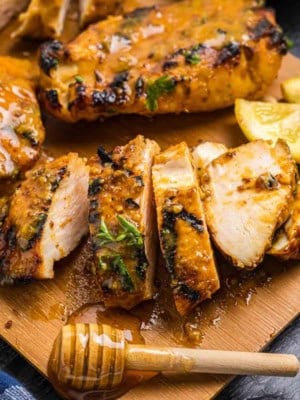 Grilled honey mustard chicken cut up on a cutting board.