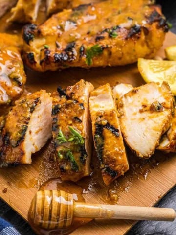 Grilled honey mustard chicken cut up on a cutting board.