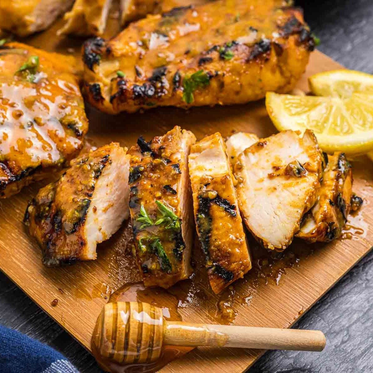 Grilled honey mustard chicken cut up on a cutting board.