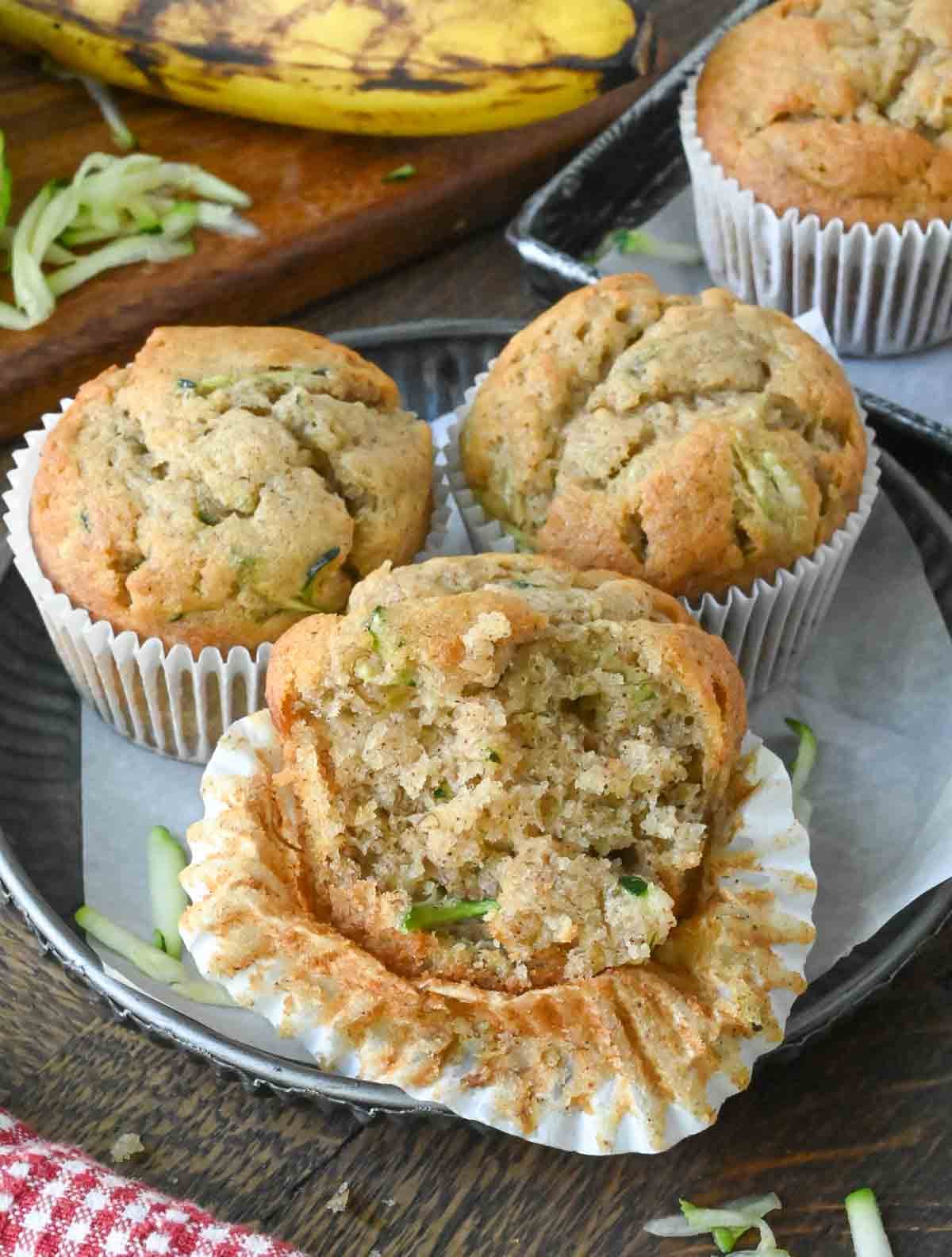 Three banana zucchini muffins on a plate.