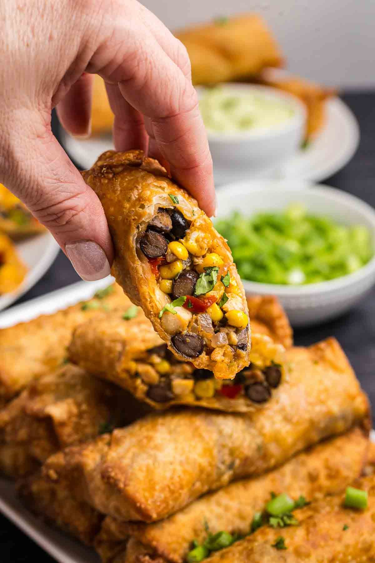 Holding up half of a tex mex egg roll.
