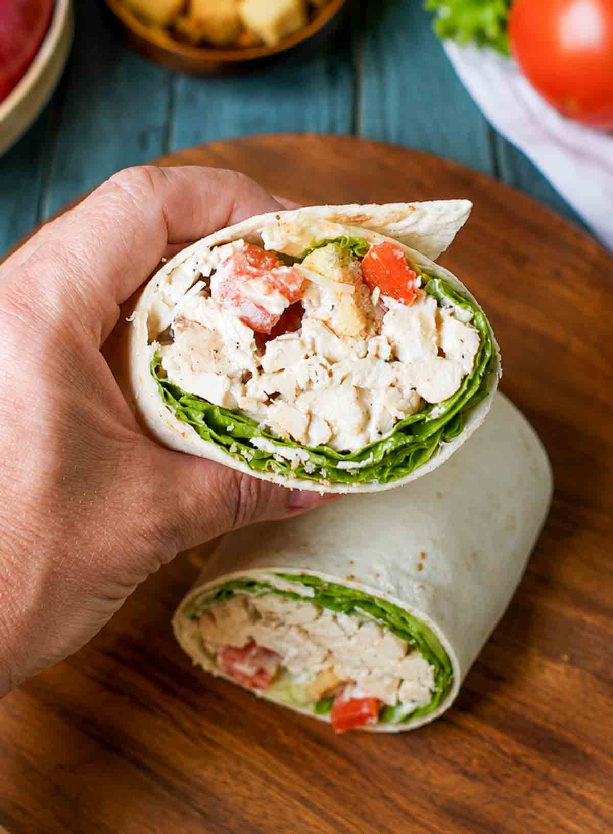 Chicken caesar salad wrap being held in a hand.