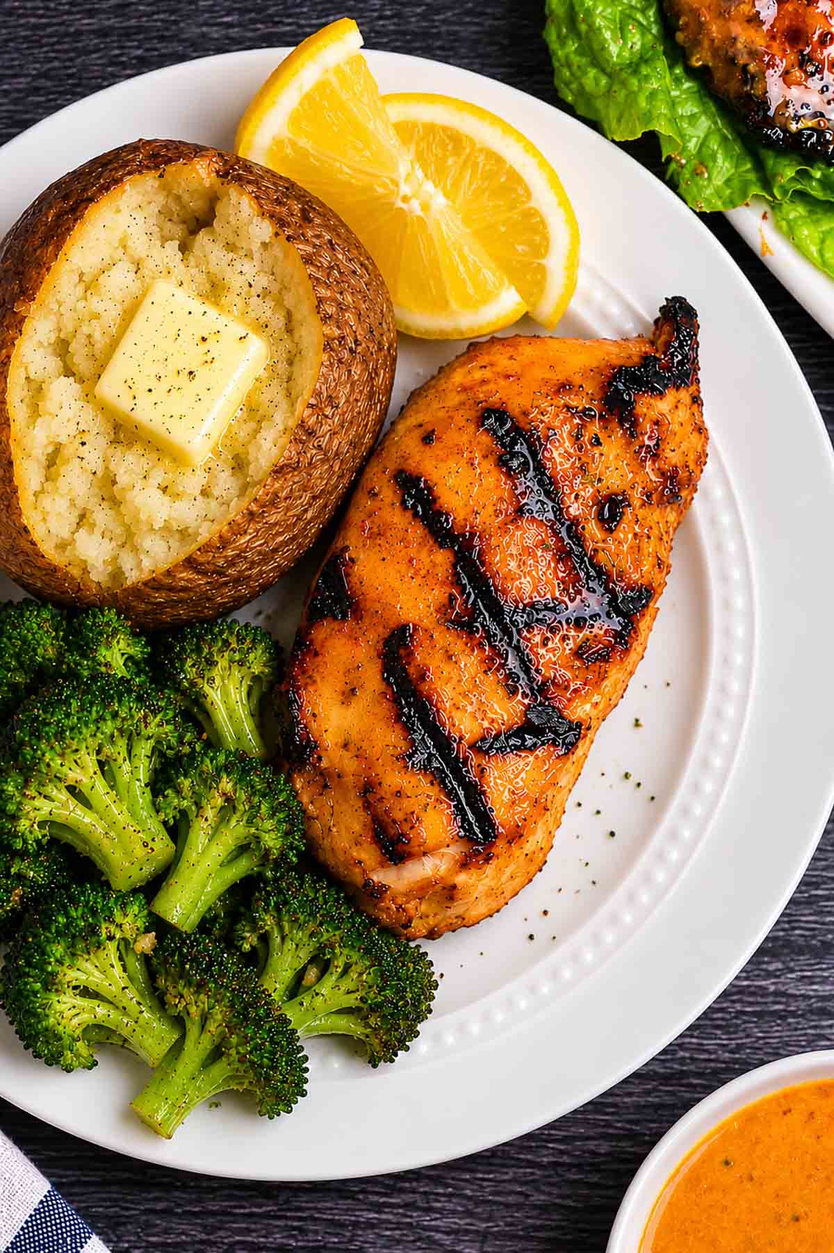 Honey mustard grilled chicken on a plate with a baked potato and broccoli.