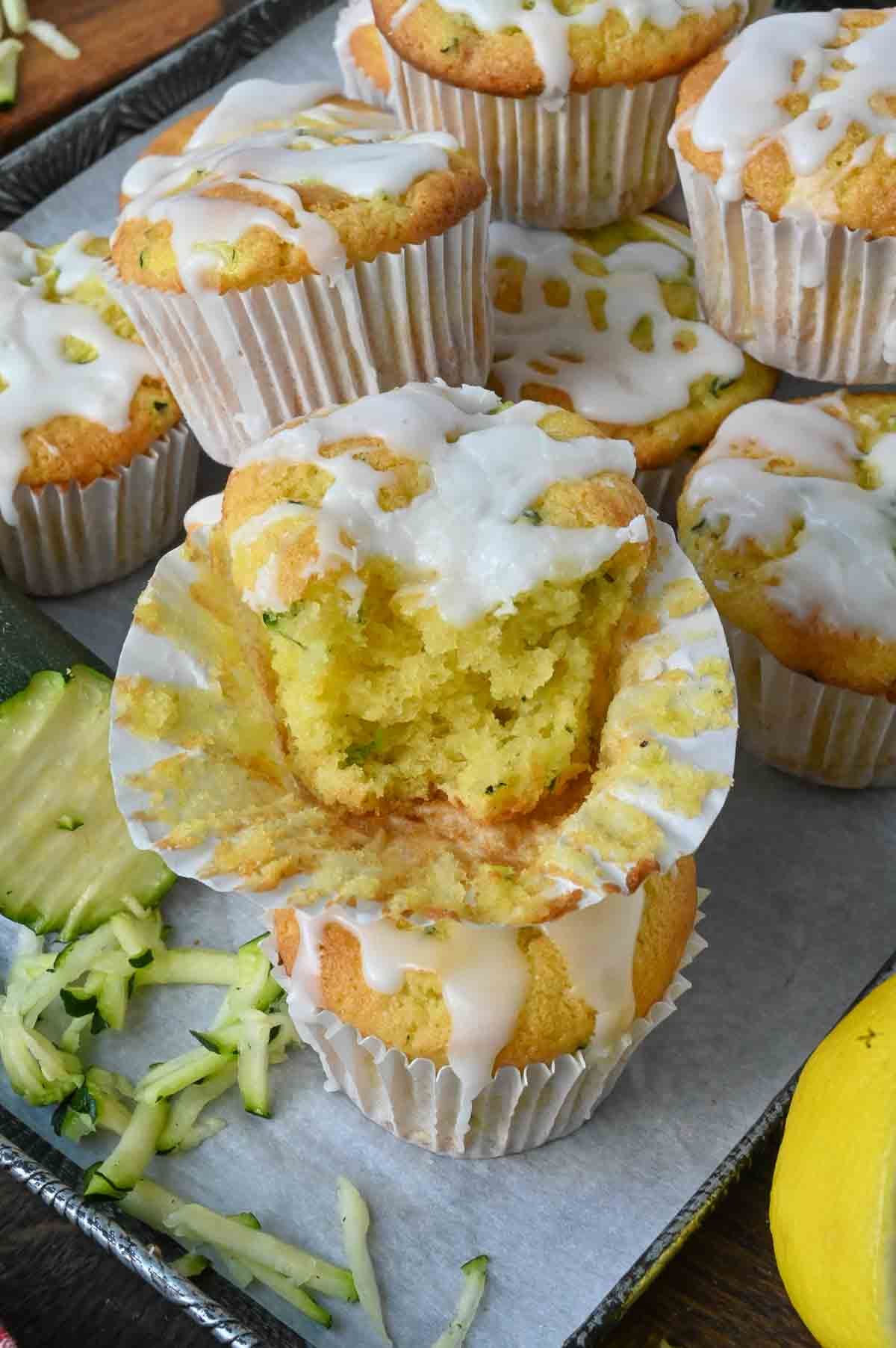 An iced lemon zucchini muffin with a bite taken out of it.
