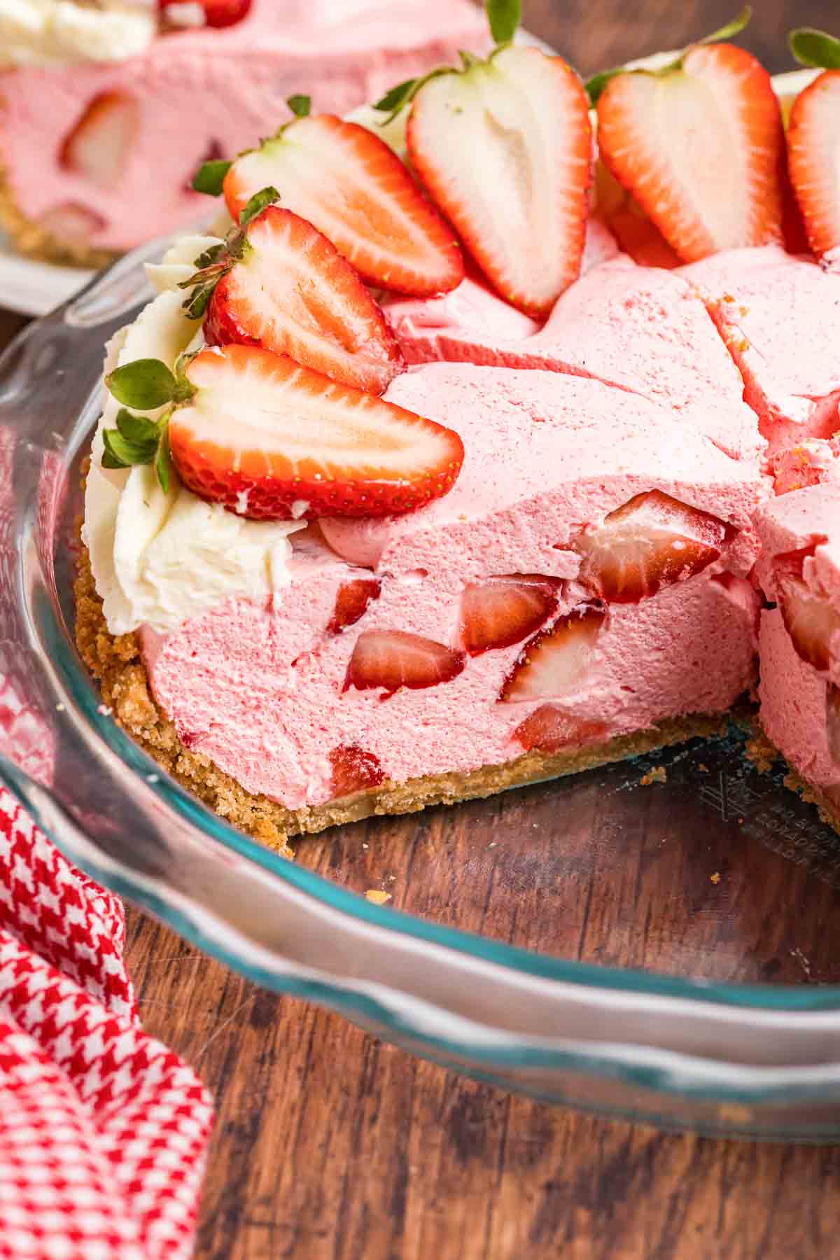 A pie dish of strawberry cool whip pie with two slices missing.