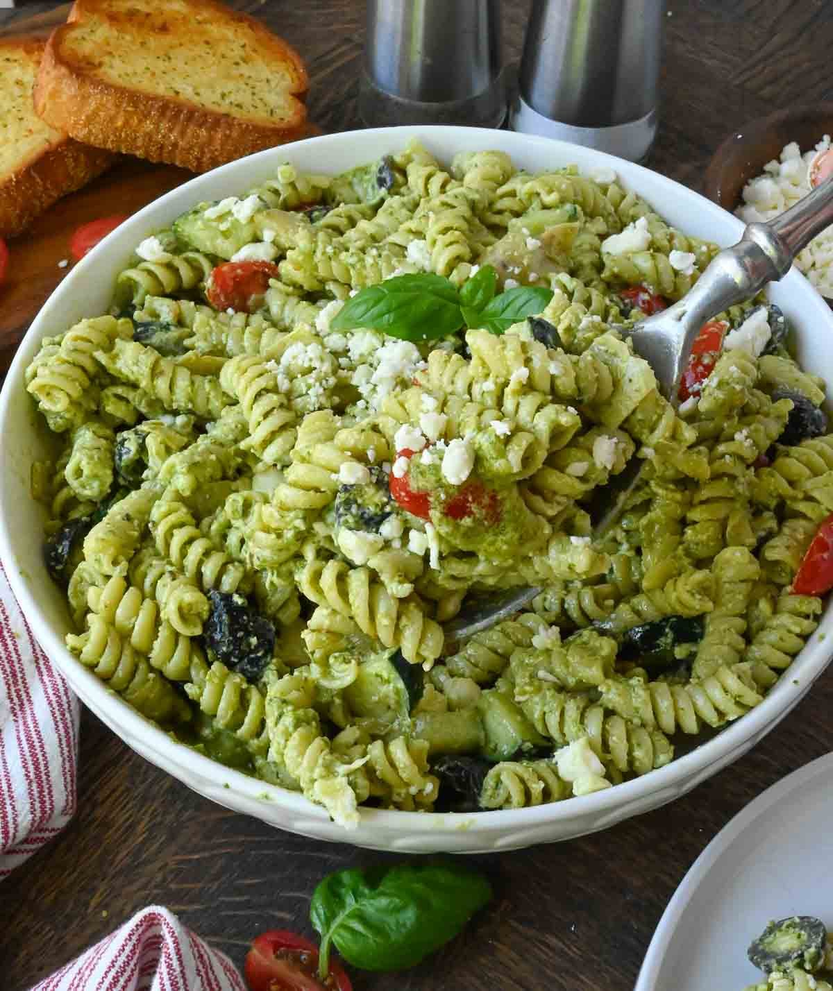 Creamy pesto pasta salad in a white bowl.
