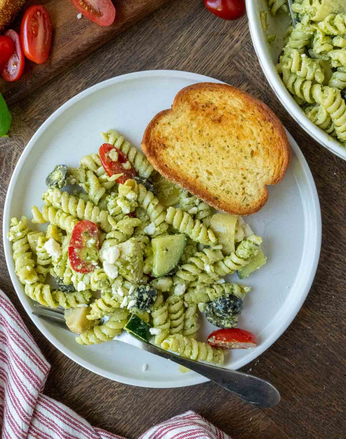 A plate of pesto pasta salad with Texas toast.