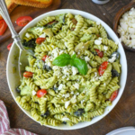 A close up of creamy pesto pasta in a white bowl.